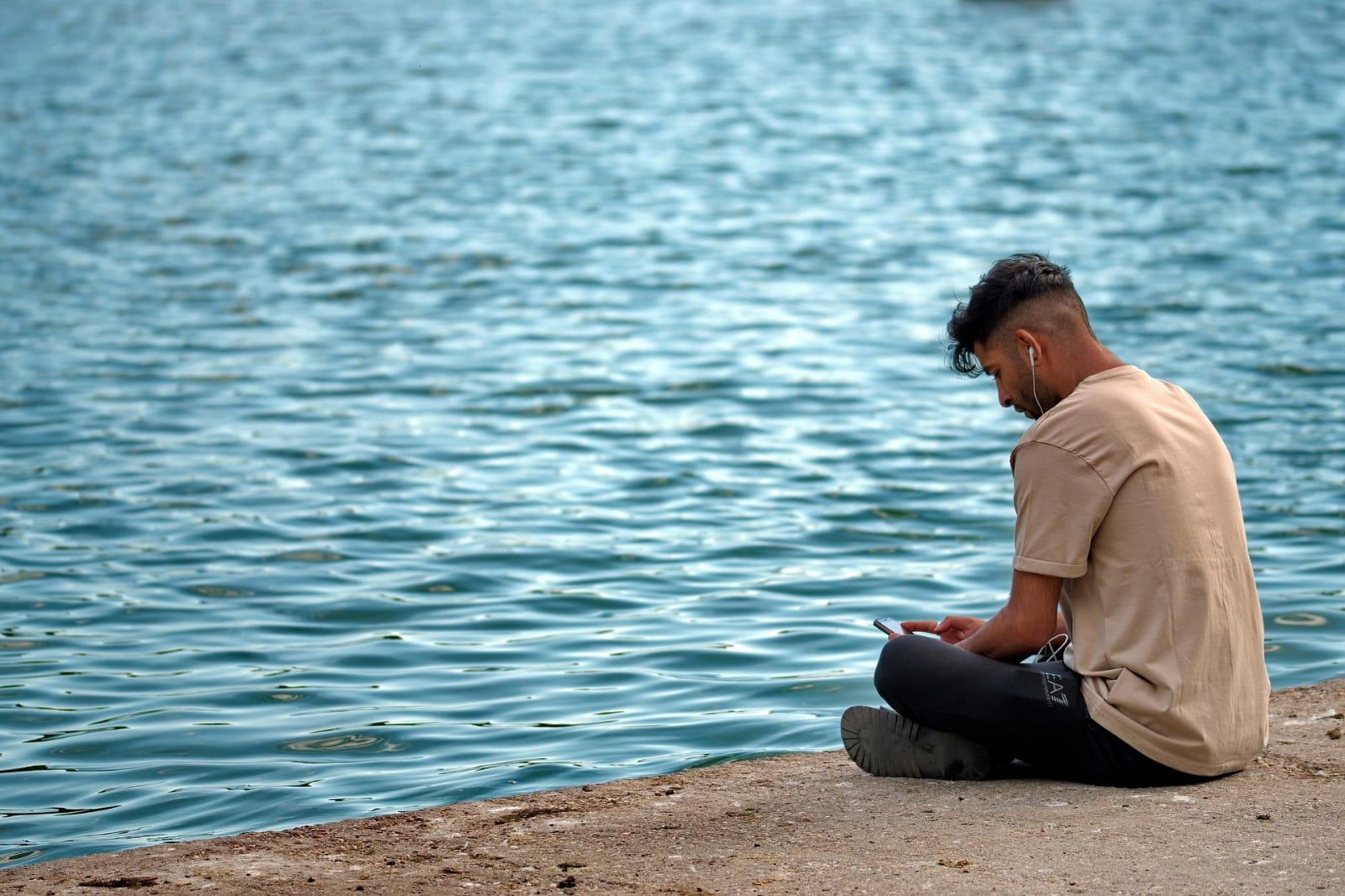 Two people sit and talk by a lake in a calm, supportive moment